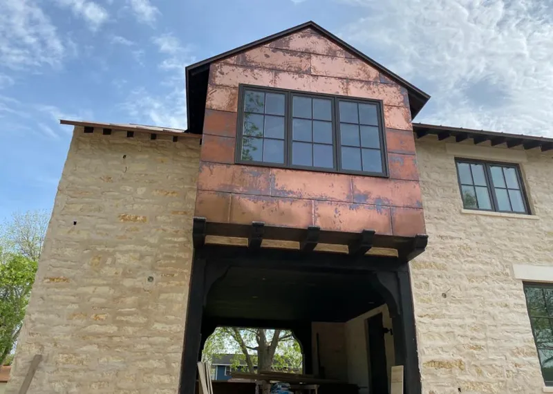 Copper metal panel facade on a stone building for Roof Repair in The Crossings
